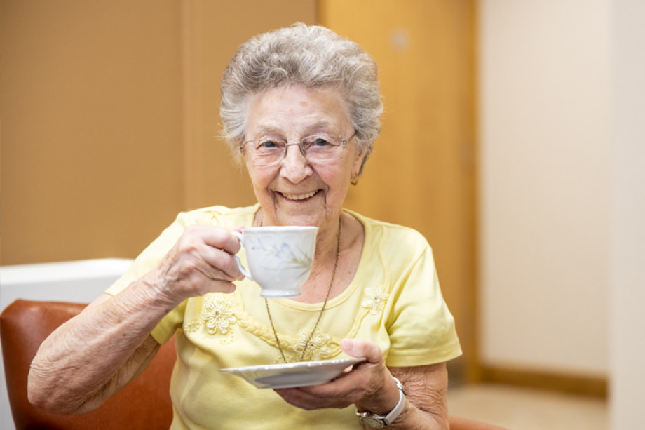 Photo of an older person holding a cup and saucer
