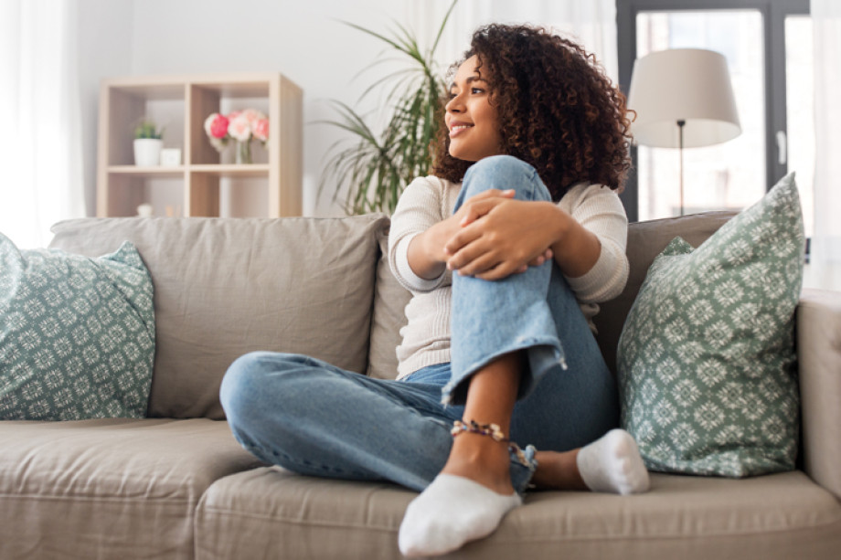 A woman sitting on a sofa holding her leg and looking to the left
