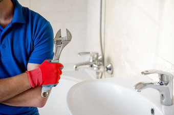 Photo of someone holding a spanner in a bathroom