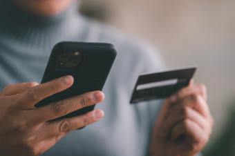 Photo of someone holding a mobile phone and a credit card