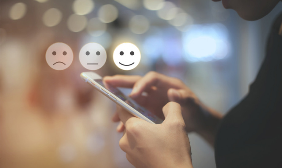 Photo of someone holding a mobile phone with a happy, sad and neutral face above it
